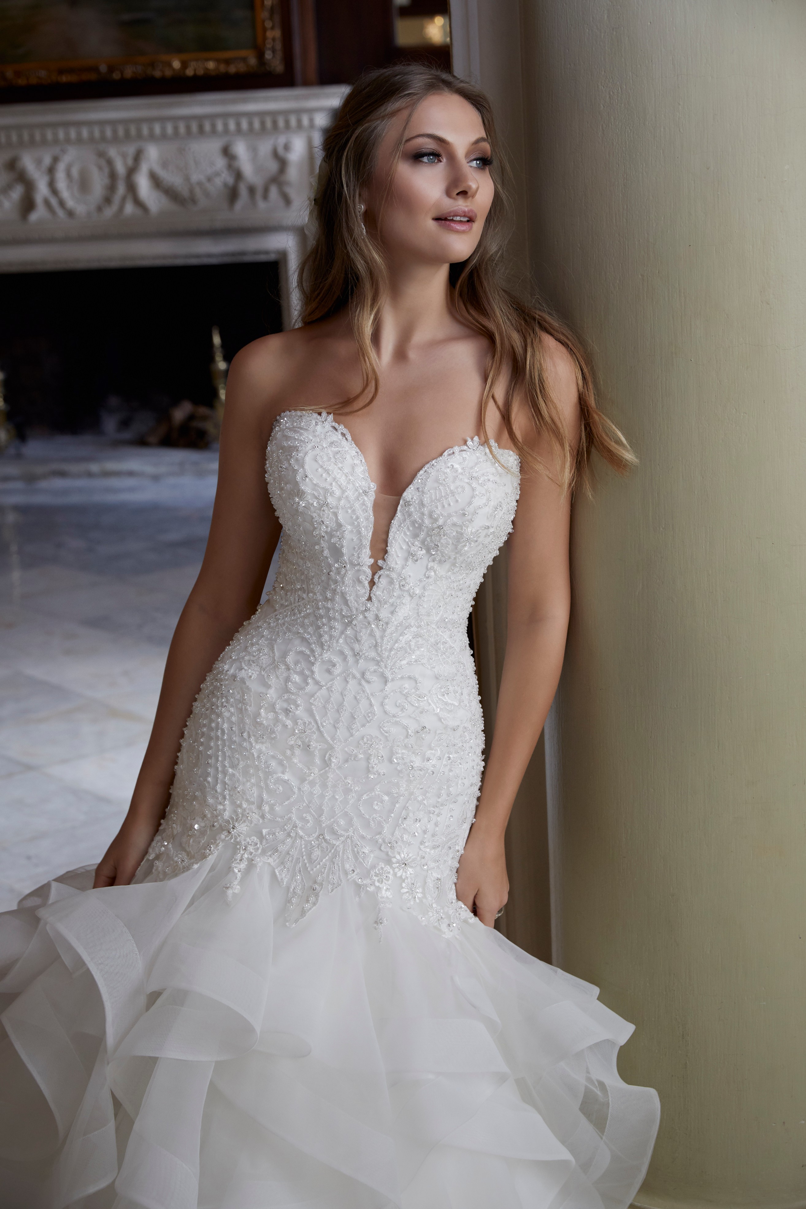 Model wearing one of our Ronald Joyce hot wedding dress trends, Didima (style 69587) – a fishtail dress with a ruffle skirt and beaded plunge bodice in ivory.