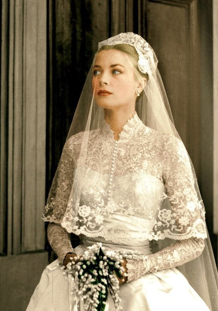 Grace Kelly on wedding day wearing lace long sleeve wedding dress with matching veil and tiara holding white bouquet