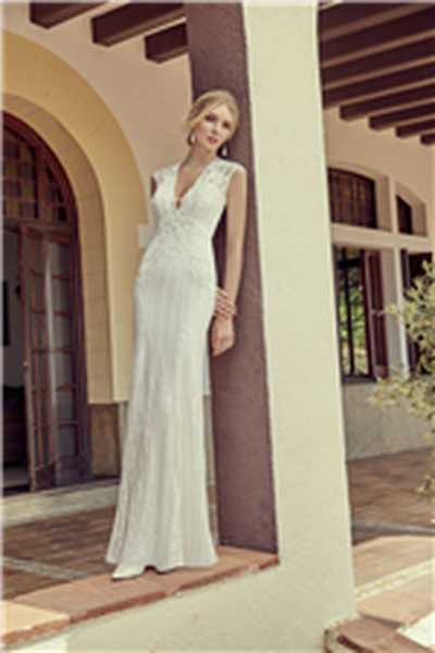 Woman standing on patio wearing fitted wedding dress with v-neckline and lace applique detail