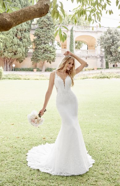Model stood in a garden wearing Ronald Joyce 69602, a strappy ivory lace fit and flare wedding dress with a plunging illusion neckline that’s suitable for small weddings