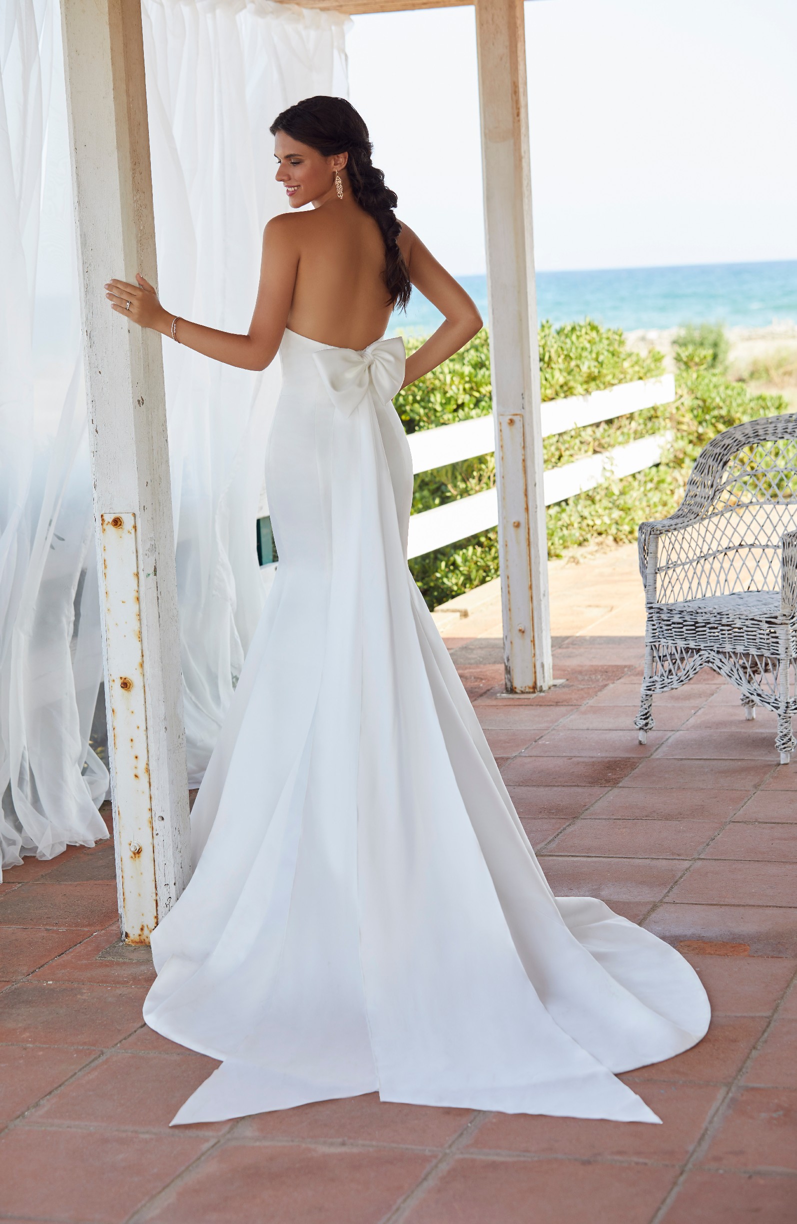Brunette woman standing on porch in classic mikado wedding dress with low back and bow detail