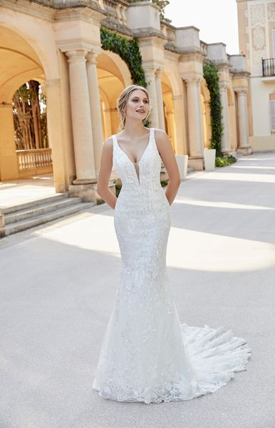 Model stood in a grand Italian courtyard in Ronald Joyce style 18503, a vintage inspired lace wedding dress with a fit and flare skirt and plunging illusion v-neckline 