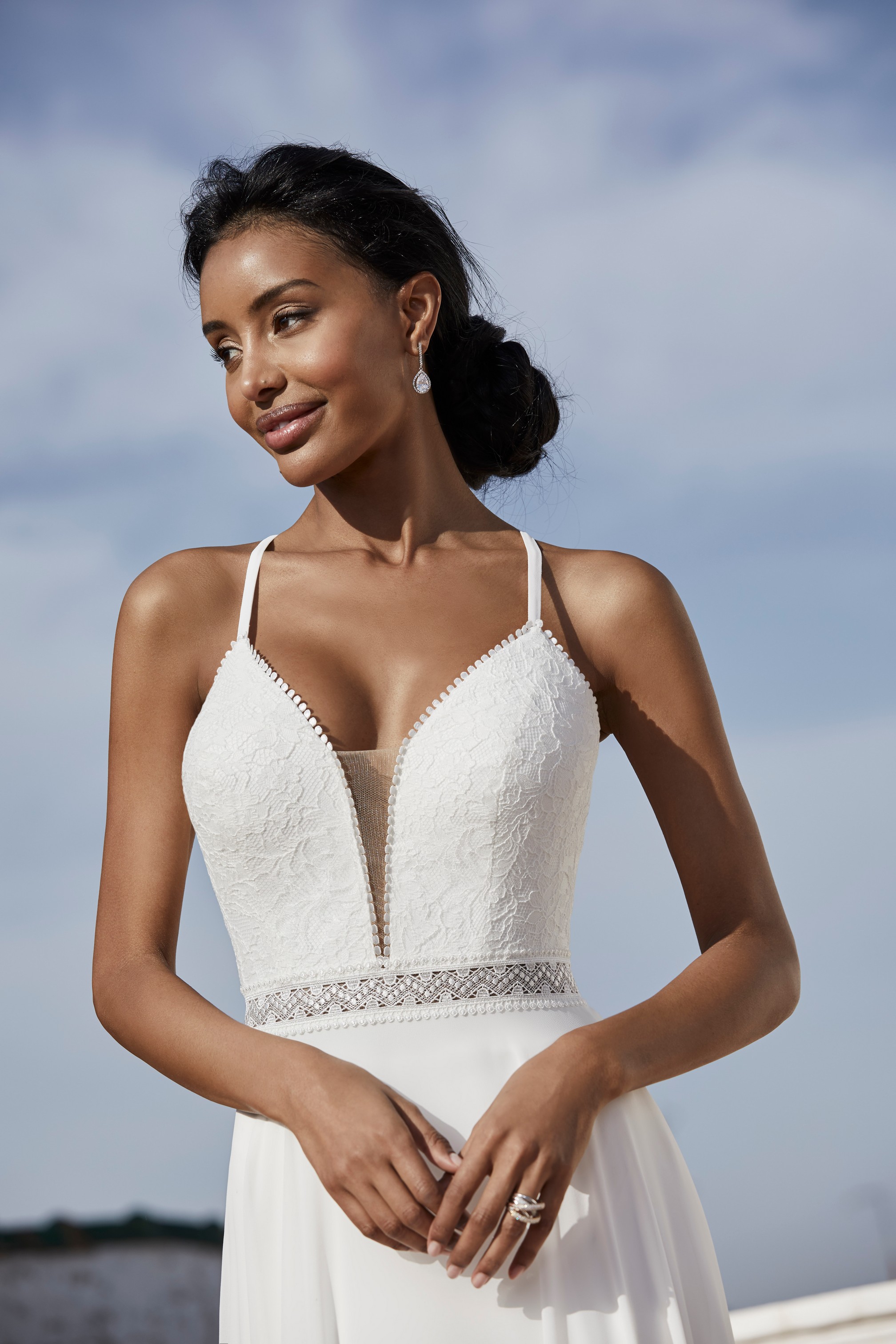 Close up of a model in Victoria Jane style 18560, a plain A-line destination wedding gown with a plunging illusion neckline, delicate straps and crochet waistband 