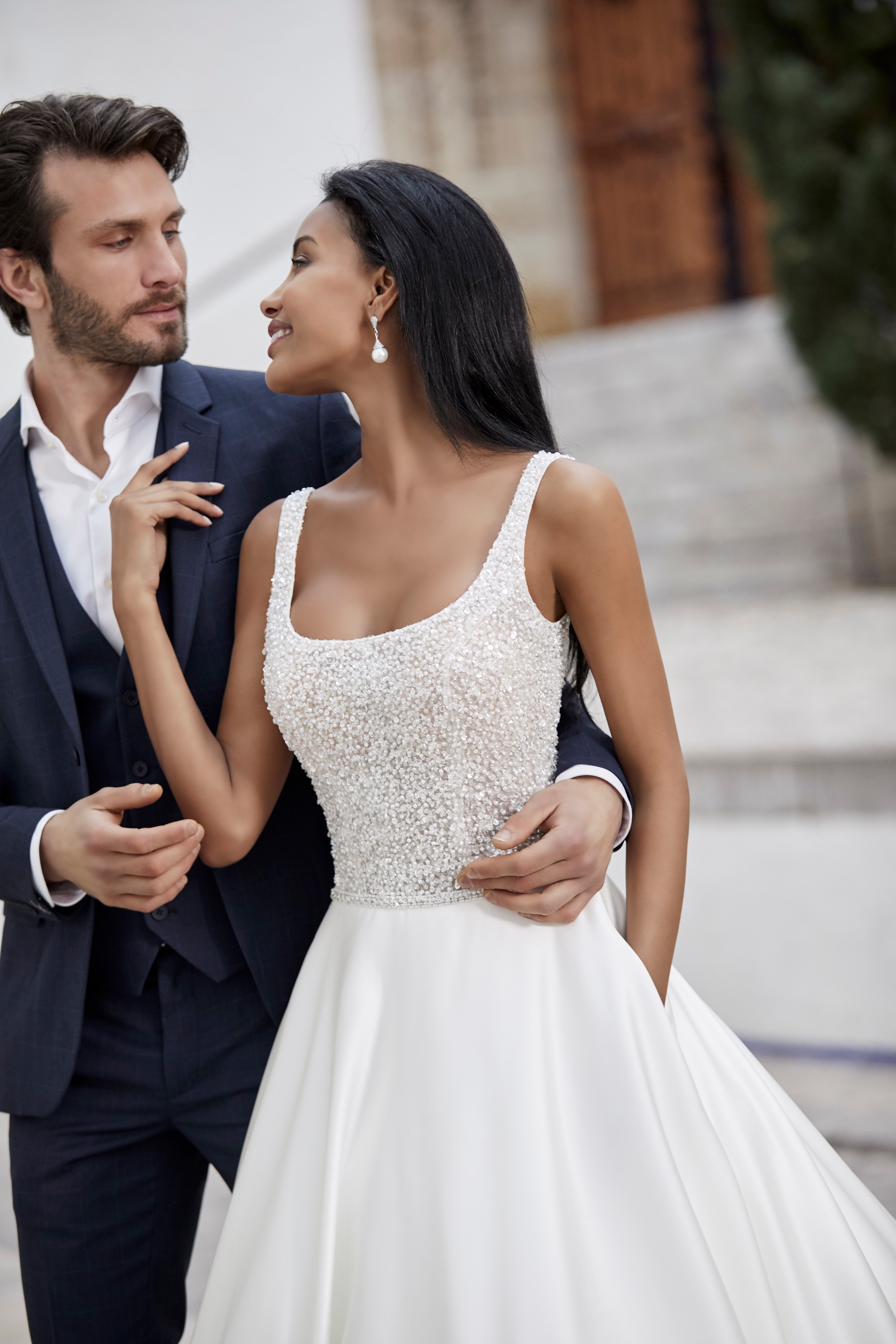 Man and woman embracing on wedding day while woman wears strappy ballgown wedding dress with beaded bodice