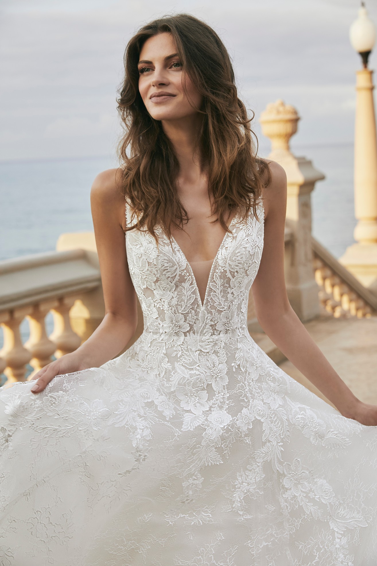  Close up of model wearing Ronald Joyce Victoria Jane destination wedding dress style 18605, an A-line lace dress with a plunging v-neckline and modesty bodice. nation wedd
