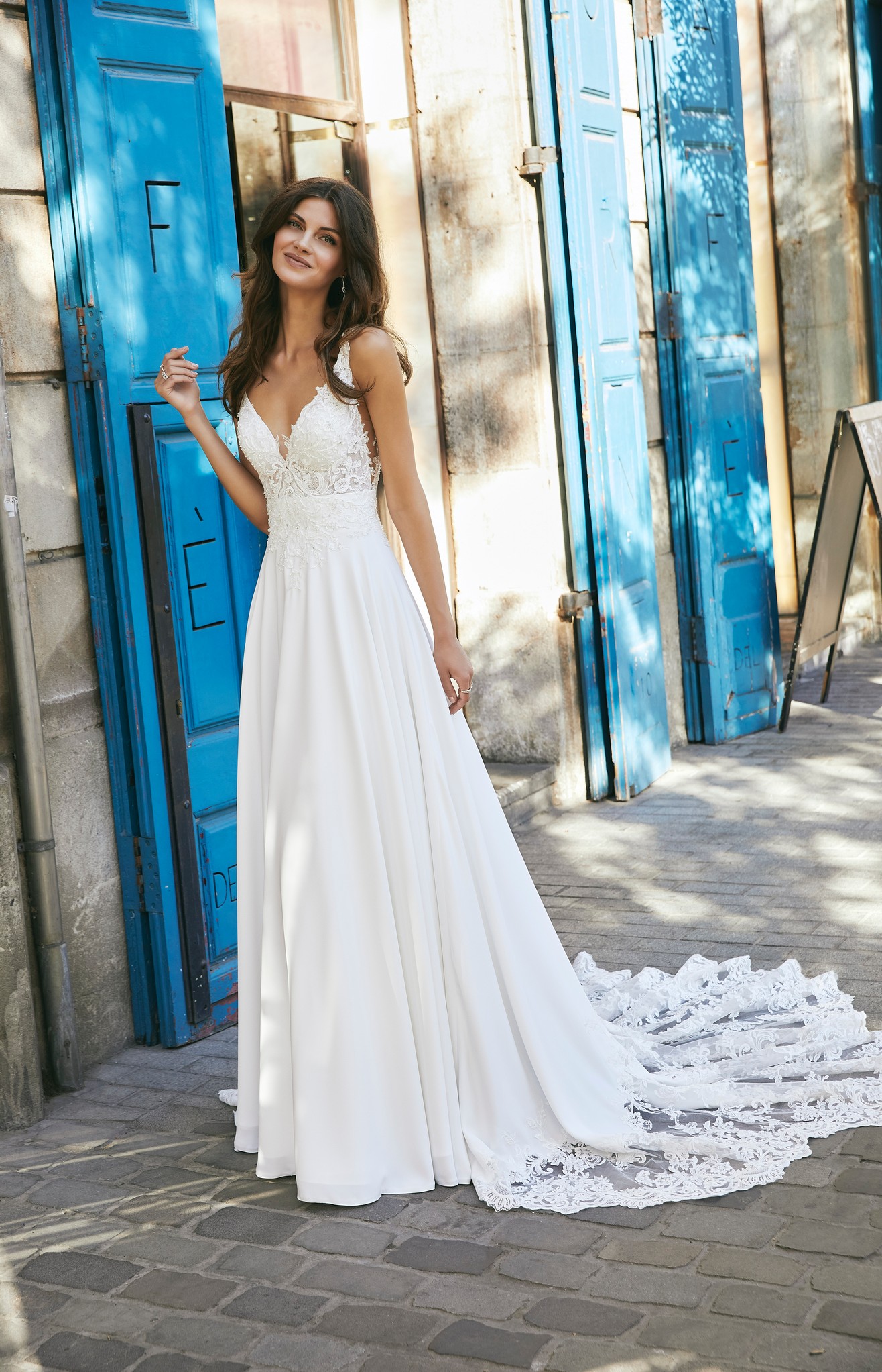 Model in Ronald Joyce destination wedding dress style 18618, a beautiful crepe and lace A-line dress with a plunging v-neckline and open back detail 