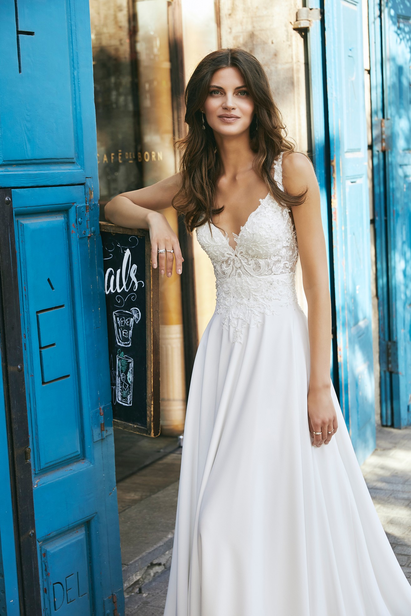 Model wearing Ronald Joyce destination wedding dress style 18618, a beautiful crepe and lace A-line dress with a plunging v-neckline and open back detail 