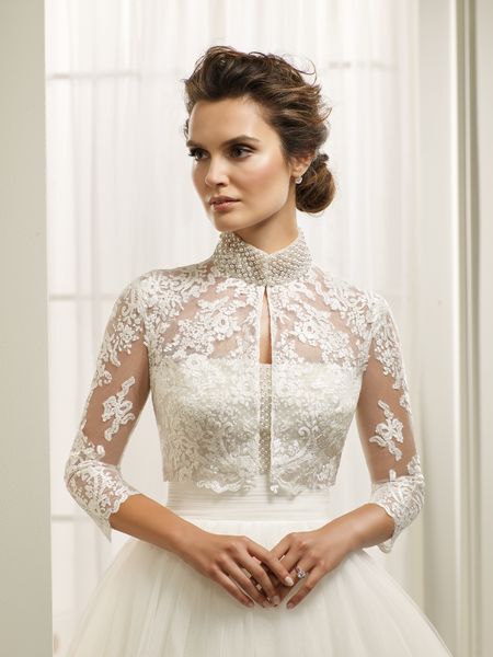 Close up of a brunette model in a strapless ballgown wedding dress and a lace illusion cropped jacket with a pearl beaded high collar that’s perfect for covering the older bride