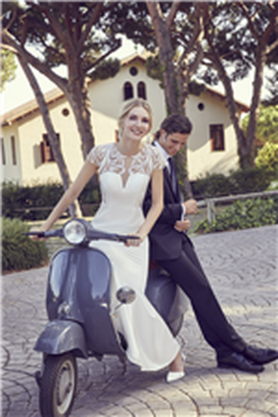 Man and Woman on moped while woman wears fitted crepe wedding dress with scoop illusion neckline with beading detail