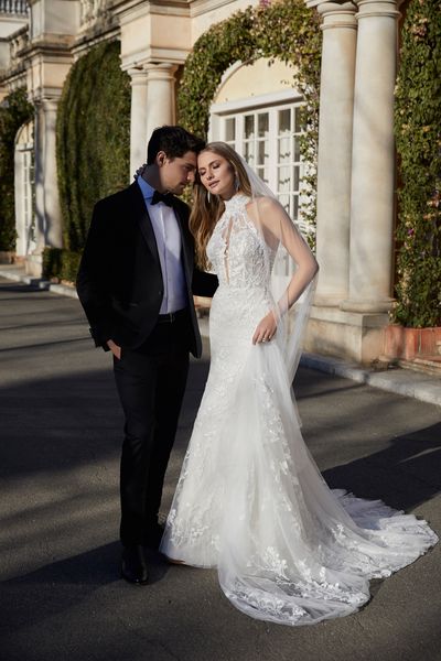 Bride and groom standing outside european villa, bride wears fit and flare wedding dress with matching embroidered veil