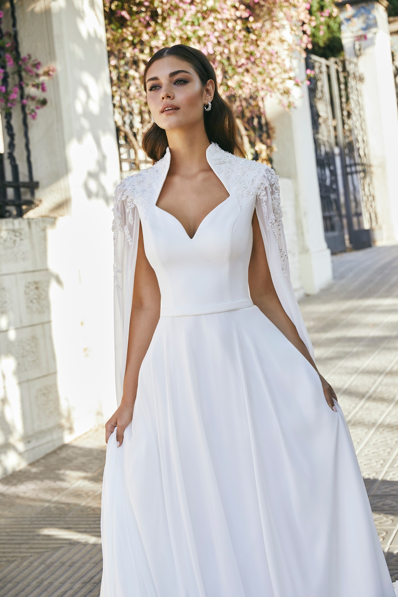 Close up of model in Ronald Joyce 69708, a plain A-line wedding dress with a sweetheart neckline, beaded Queen Anne collar and attached chiffon cape