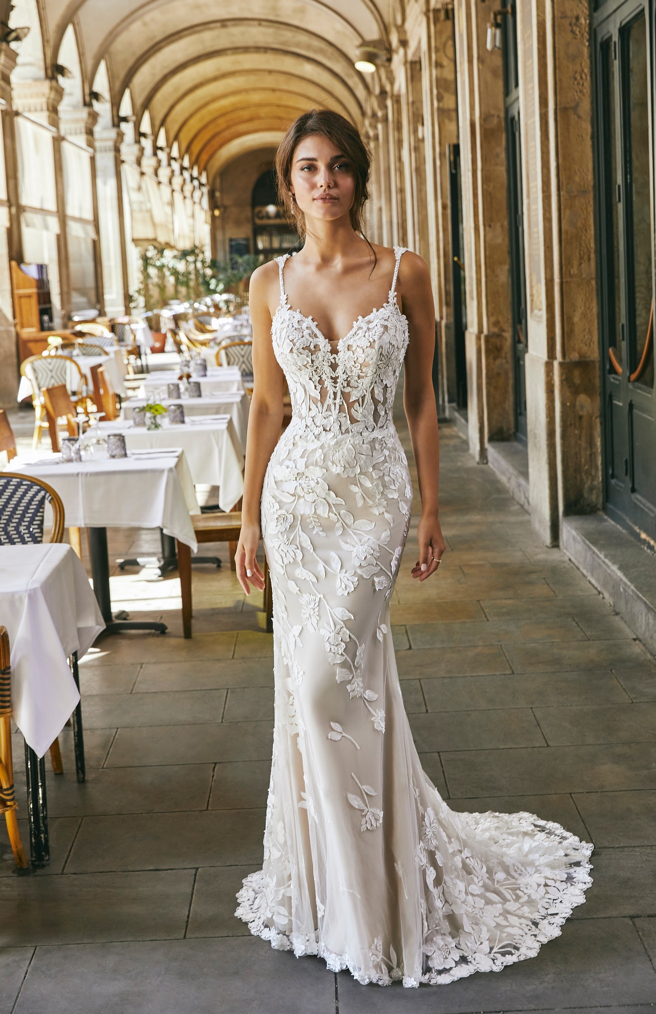 Lady standing in outdoor cafe wearing fit and flare tulle and lace applique wedding dress with sweetheart neckline and beaded straps
