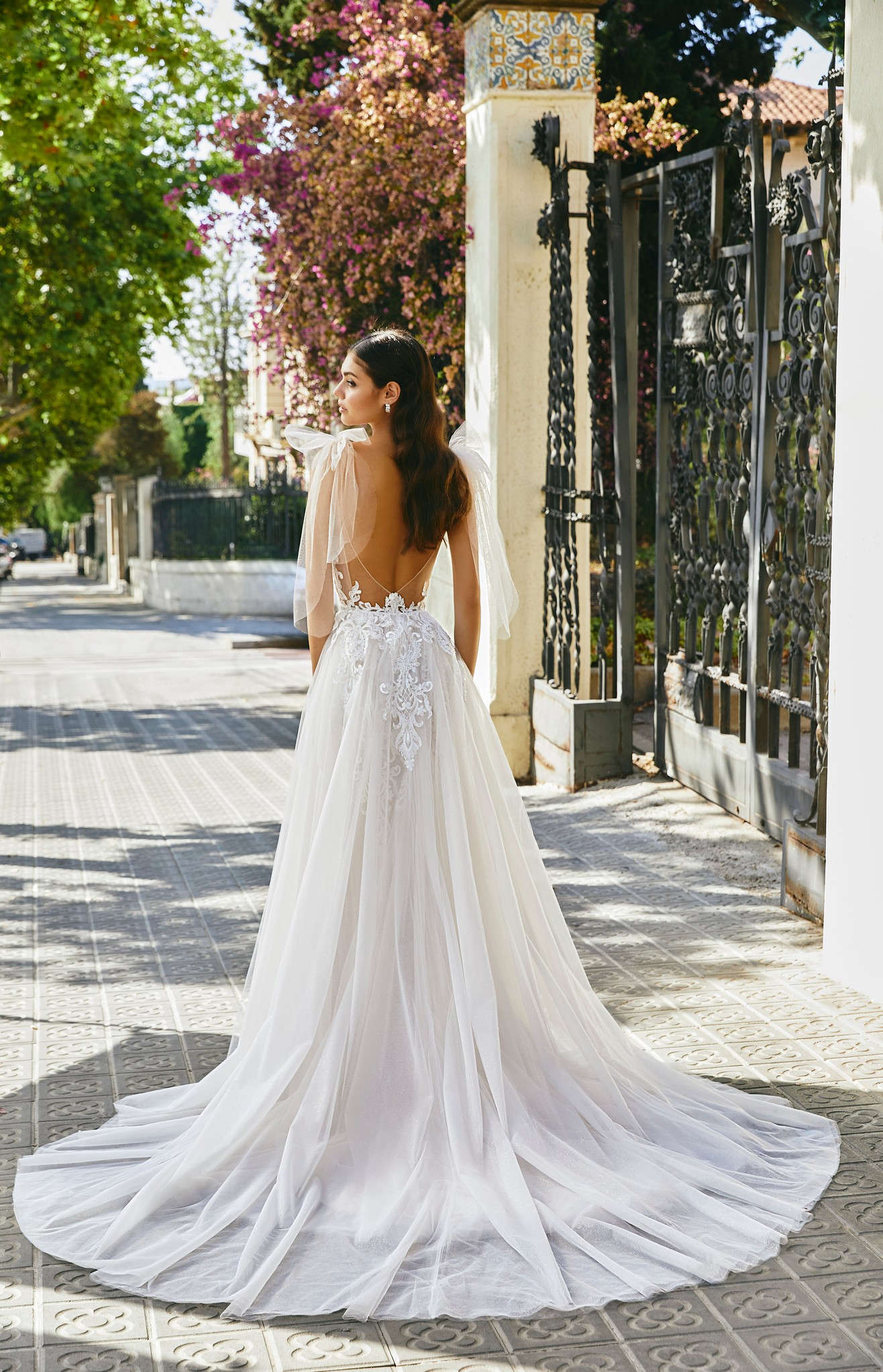 Woman standing on street in Barcelona wearing tulle wedding dress with low illusion back and floral appliques