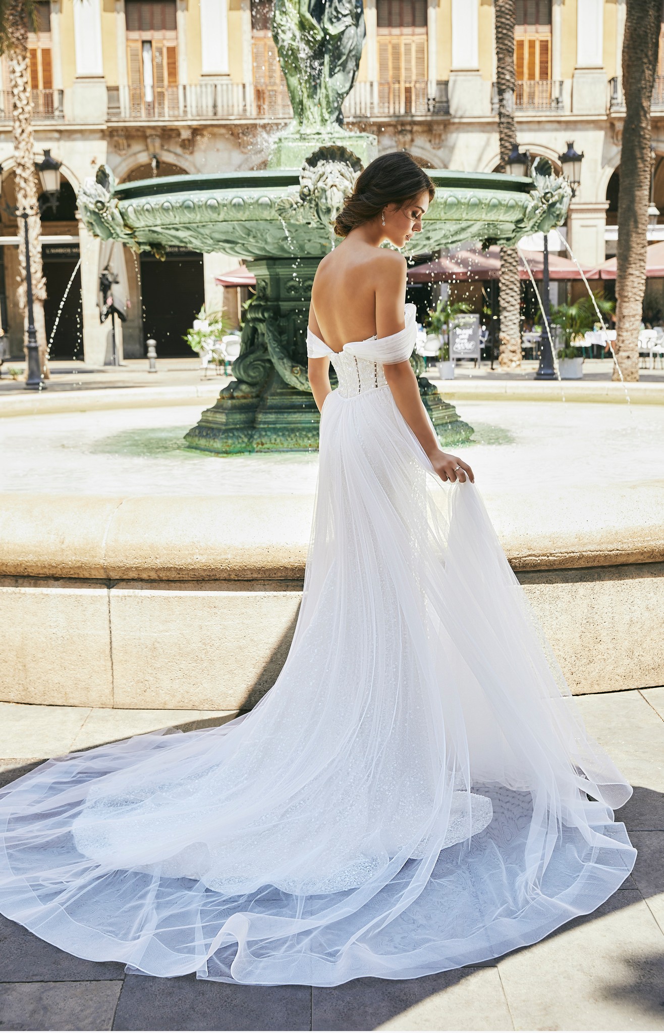 Back profile of model wearing Ronald Joyce wedding dress style 69722, a pearl-beaded fit and flare off the shoulder wedding dress 
