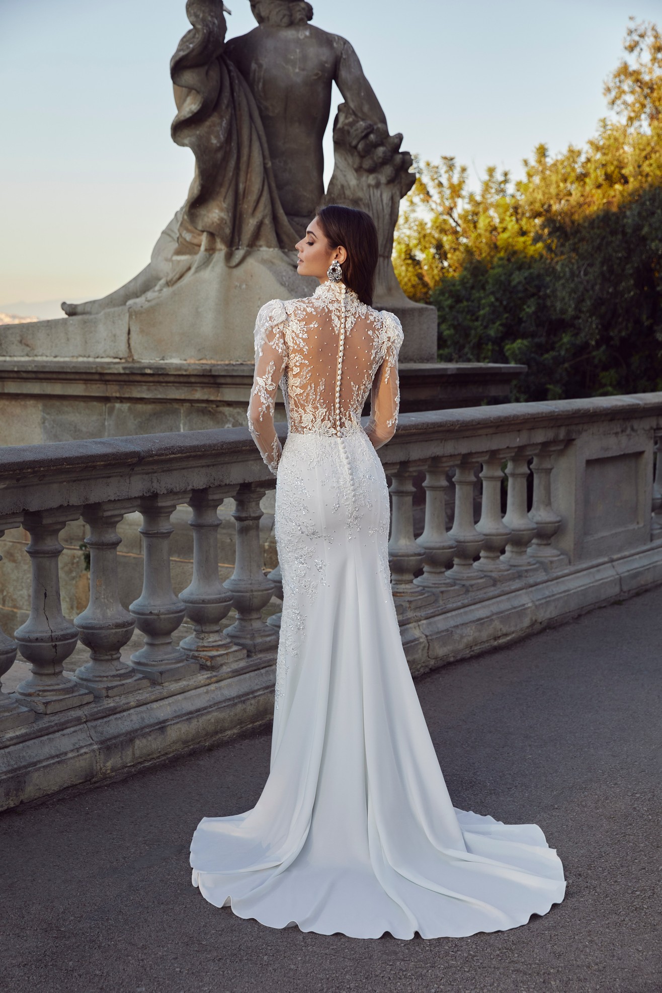 Back profile of woman wearing fitted white wedding dress with sheer illusion back