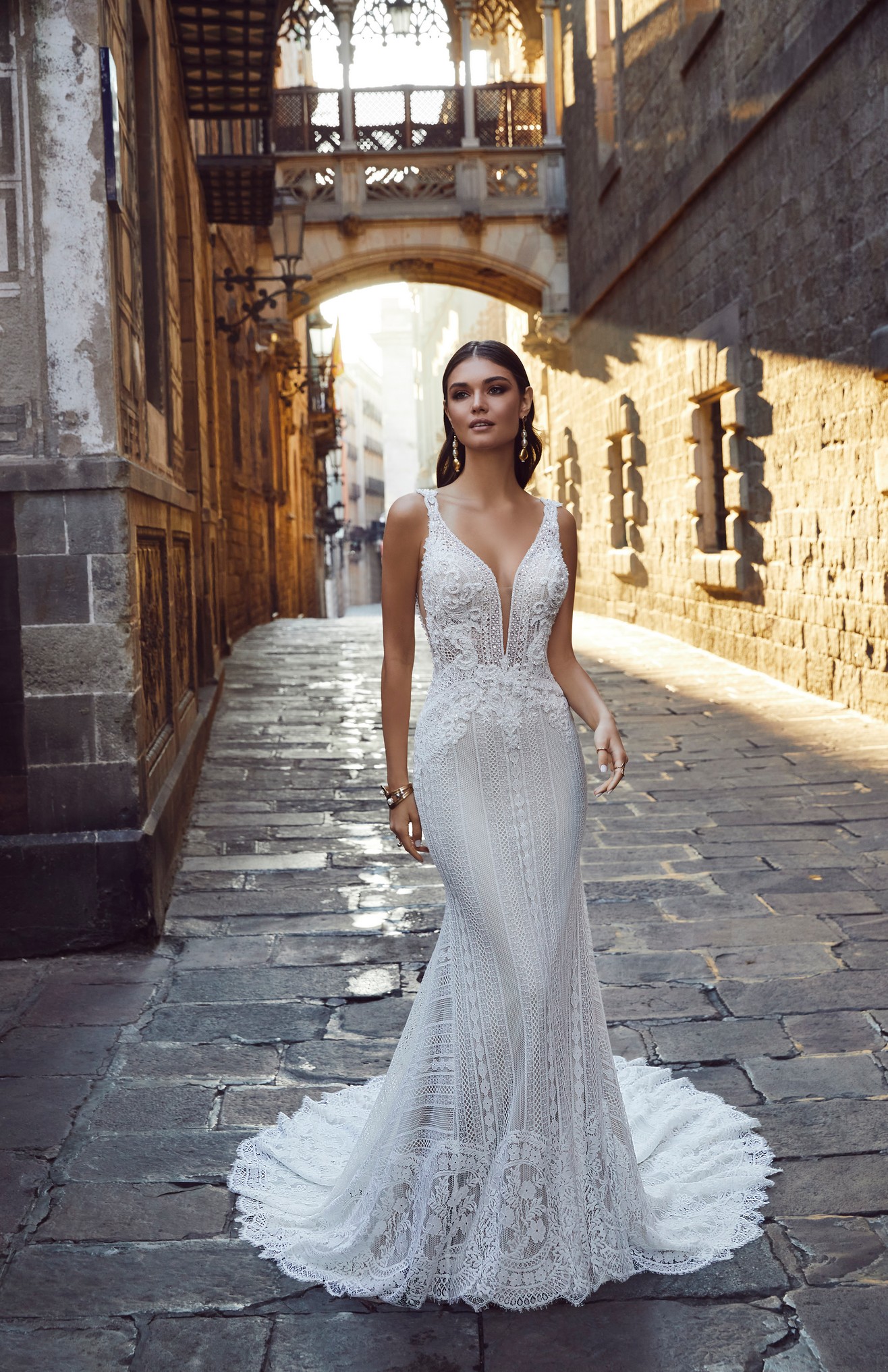 Woman standing in street wearing boho lace fitted wedding dress 