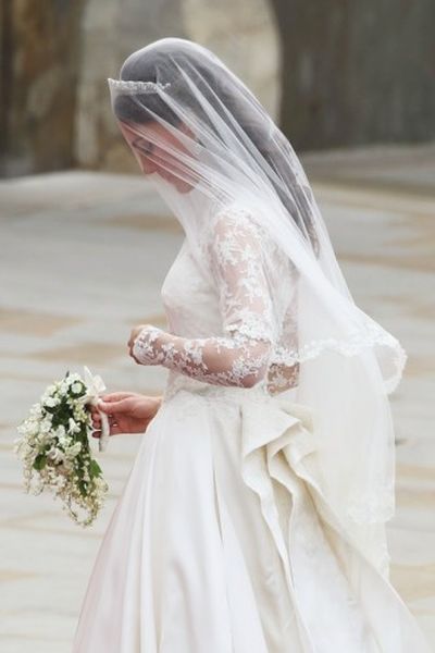 Close up image of Kate Middleton on wedding day wearing lace long sleeve wedding dress with matching veil and diamond tiara 