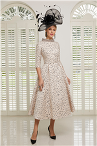 Model wears a black fascinator and Veni Infantino 991505, a 2020 cream and black spotty A-line calf-length mother of the bride dress with ¾ length sleeves in jacquard fabric
