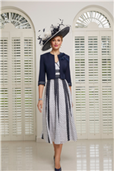 Model wears a navy and ivory hat and Veni Infantino 991512,  an ivory A-line calf-length dress with navy heart and dot print and lace trim detail. Model also wears a ¾ navy cropped jacket