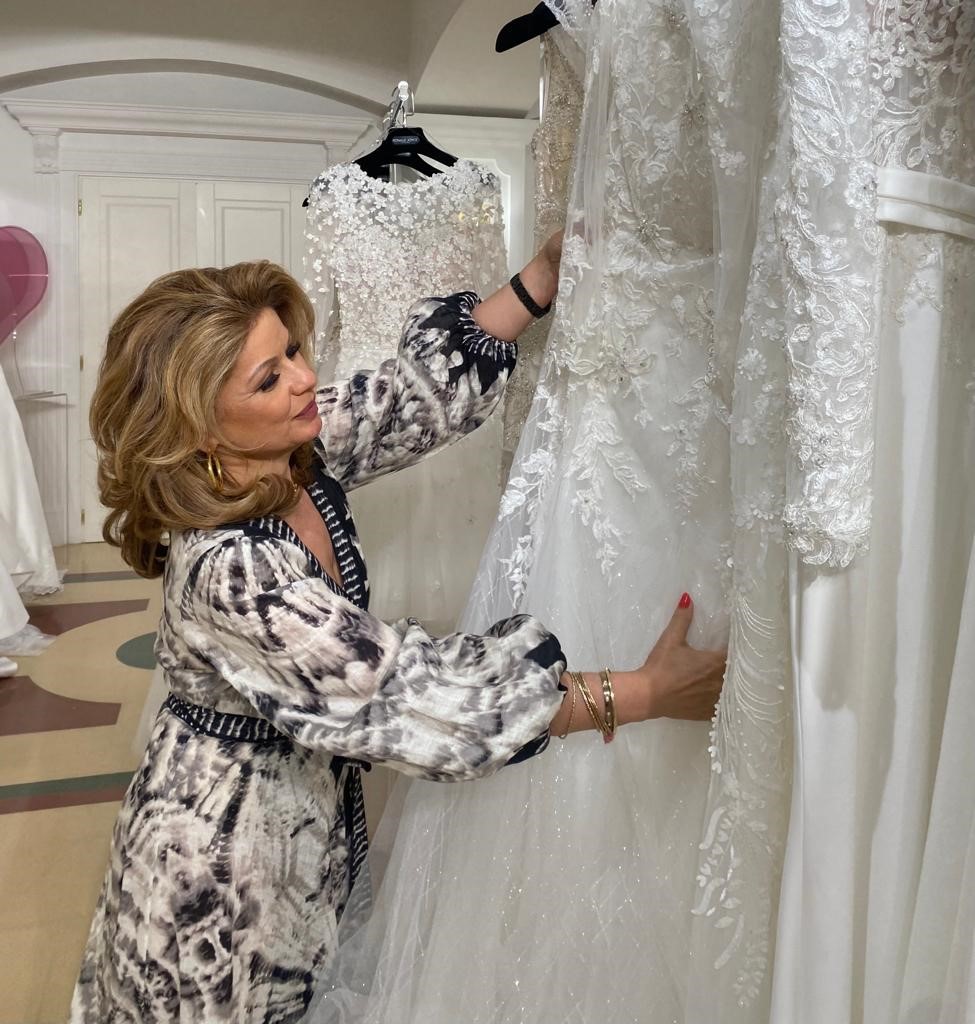 Award-winning wedding dress designer Veni Infantino admiring a lace wedding dress 