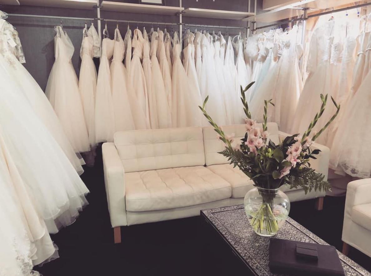 Rails of hanging wedding dresses in a waiting area complete with a vase of flowers at the Bridal Studio in Dollar in Scotland
