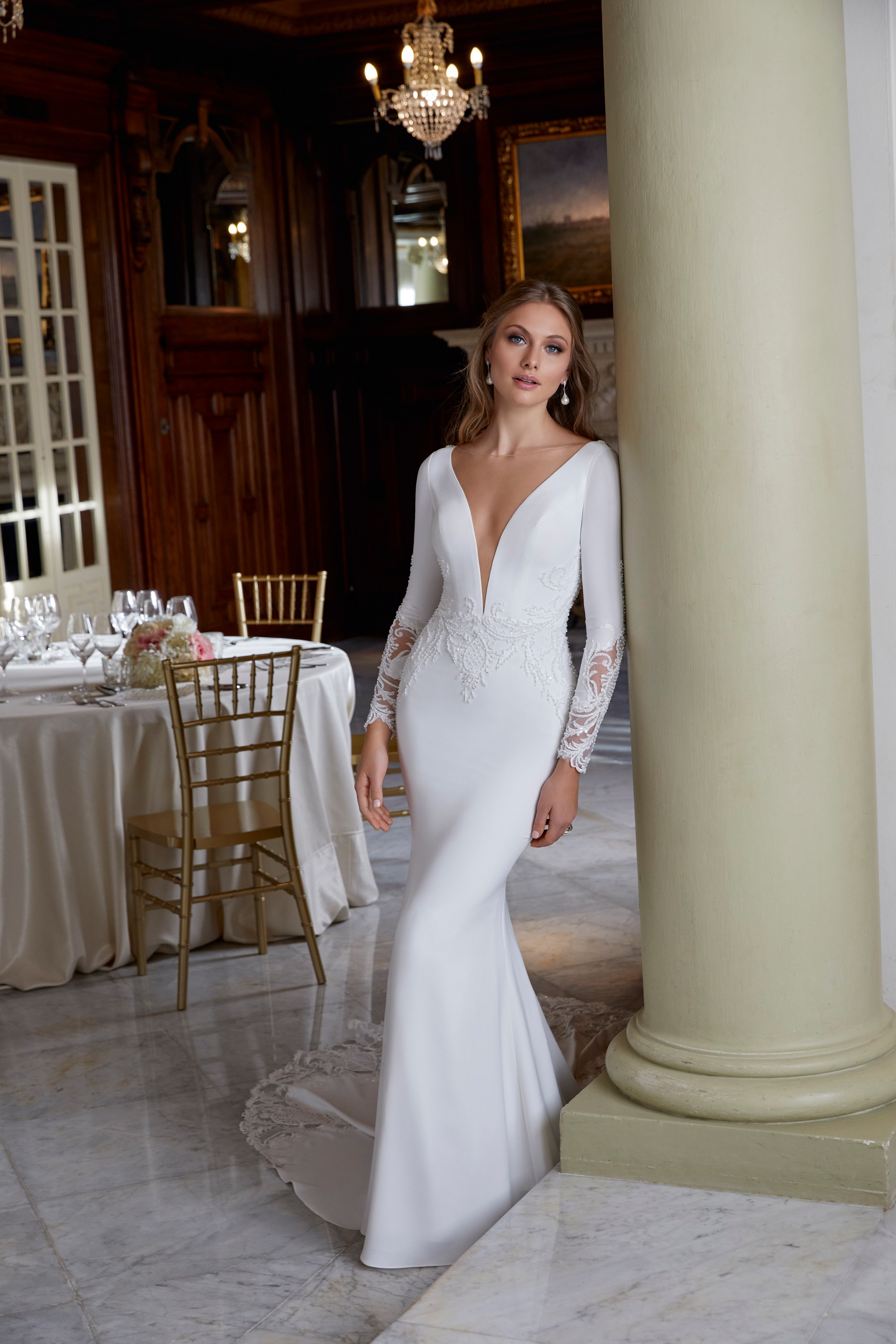 Model in one of our Ronald Joyce wedding dress trends, Doris (style 69573) – an ivory fit and flare dress with a plunging v-neckline, long sleeves and lace embroidery detail