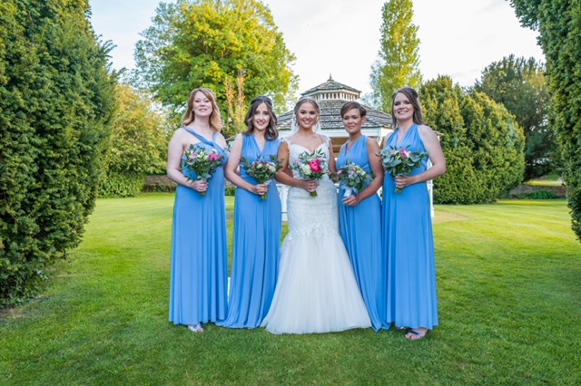 Bride on her wedding day with bridesmaid in vibrant blue long dresses