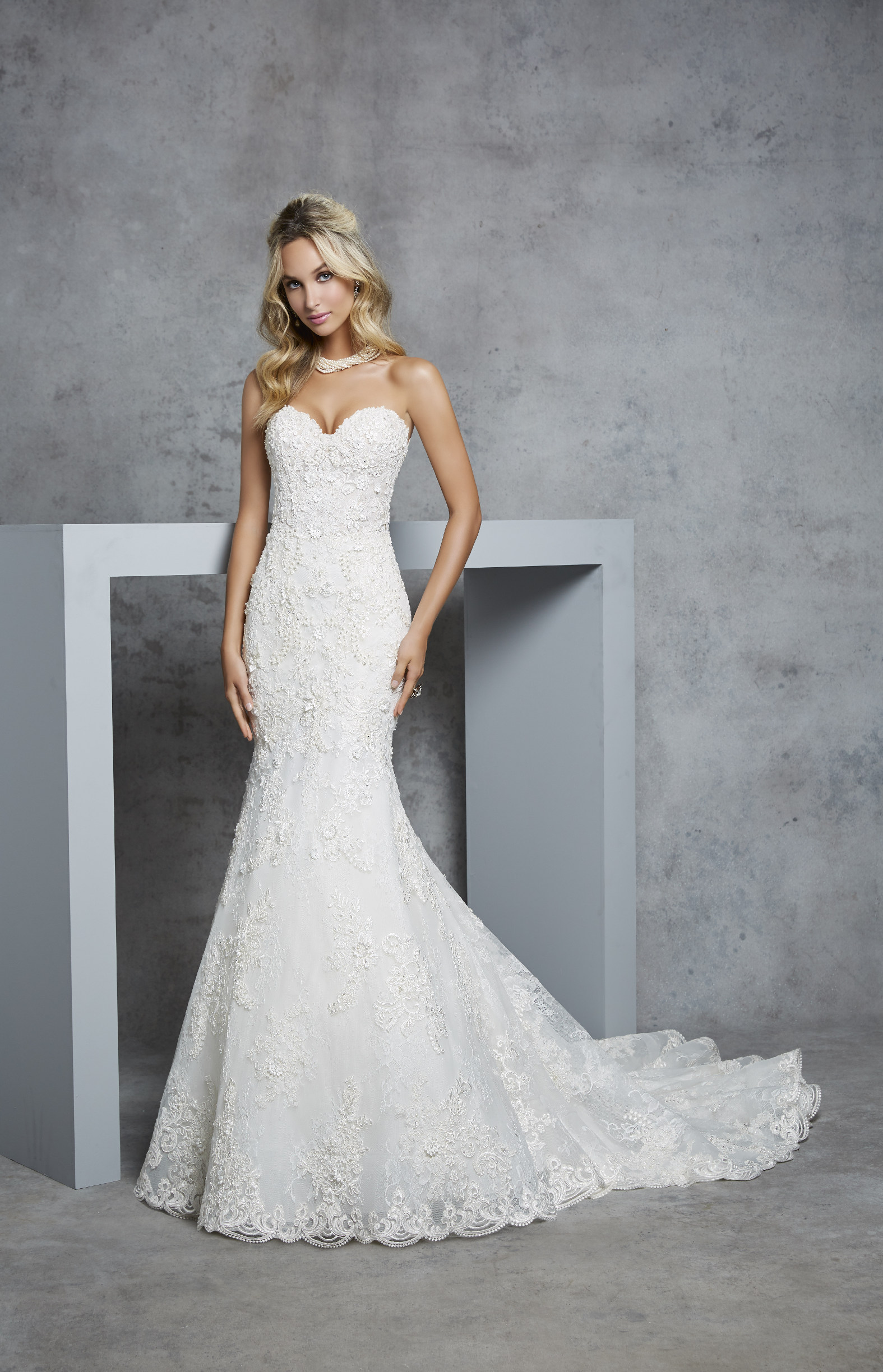 Model in Ronald Joyce 69416, an ivory fit and flare wedding dress silhouette with a strapless sweetheart neckline and beautiful continuous lace detail.