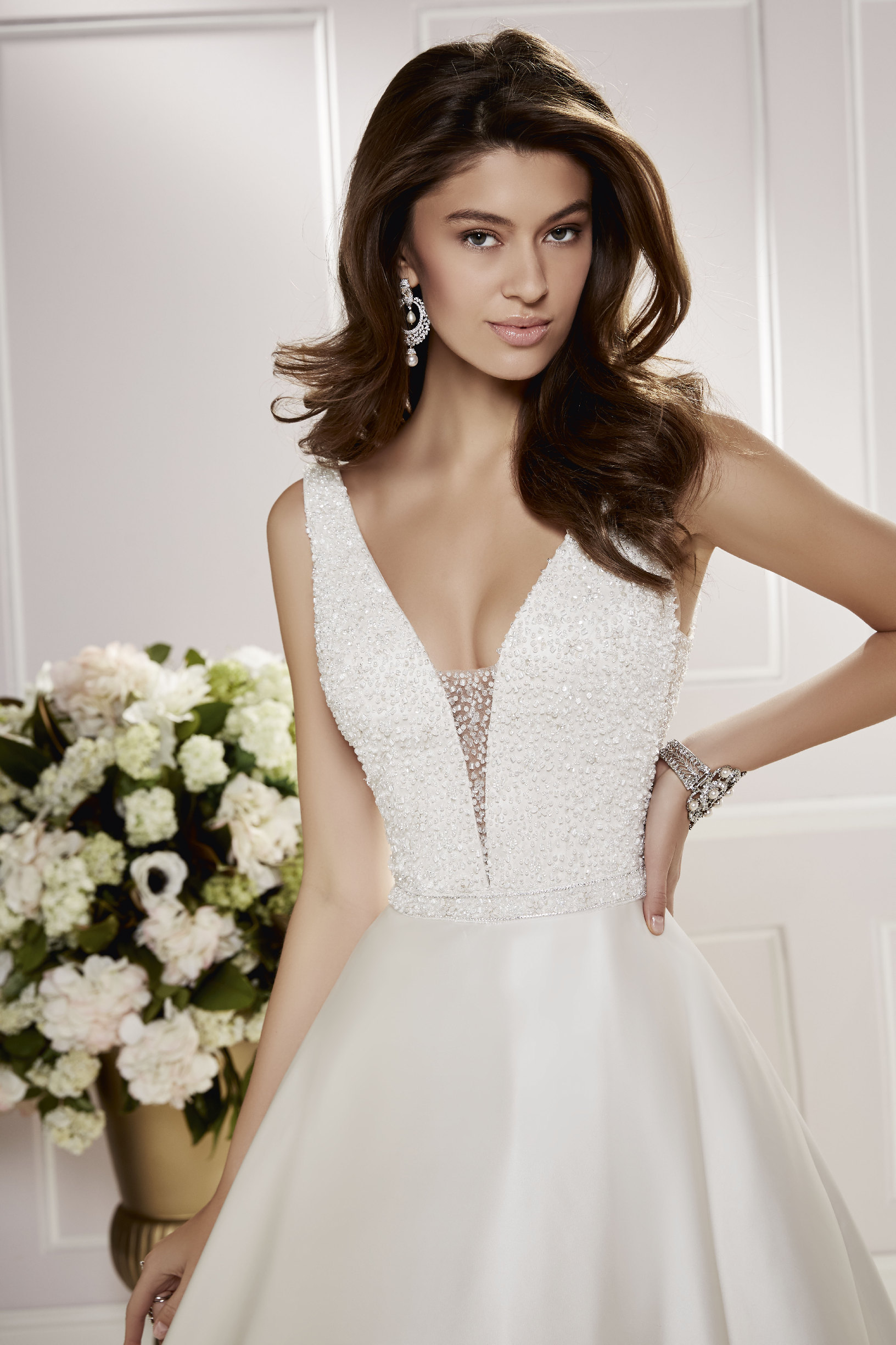 Brunette model in Ronald Joyce wedding dress 69466, a classic v-neck A-line gown with a beaded bodice and satin skirt that's perfect if you need a wedding dress quickly.