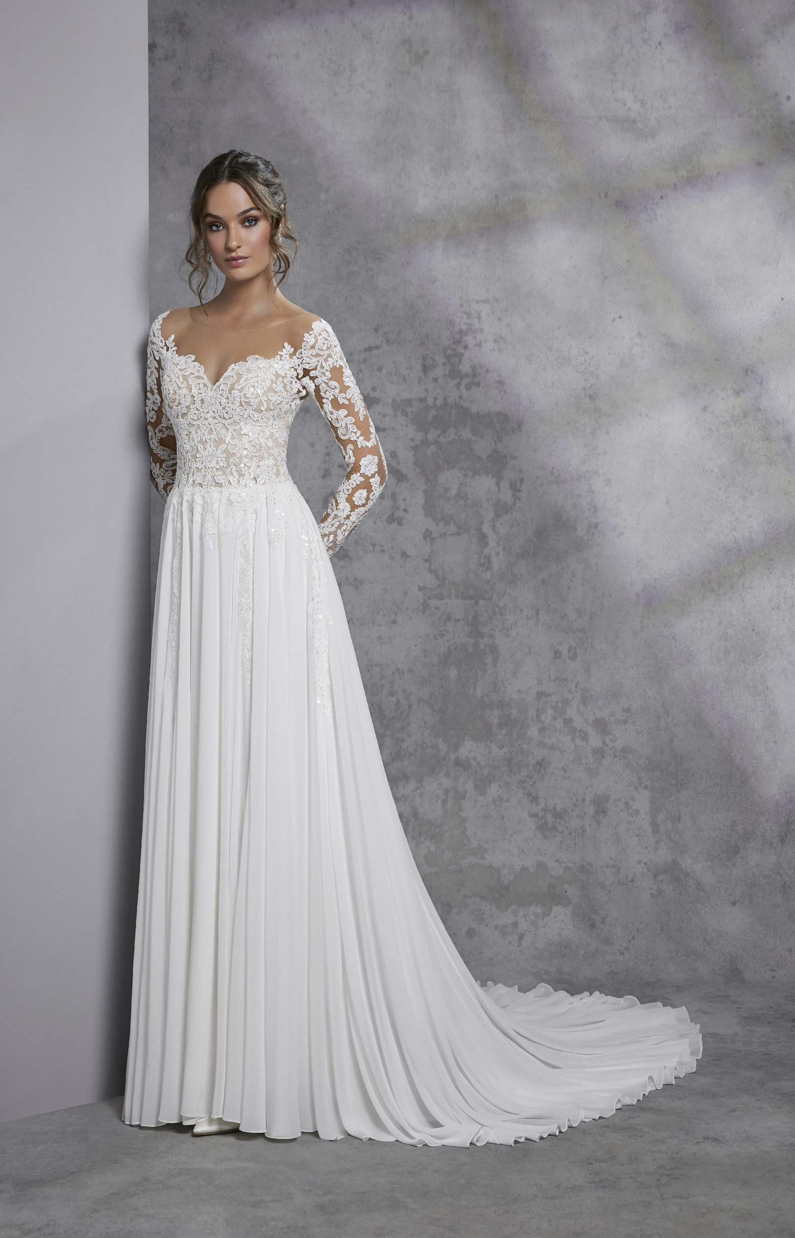 Model in Ronald Joyce style 18317, an elegant A-line boho wedding dress with off-the-shoulder long lace sleeves, a beaded sweetheart bodice and contrasting plain chiffon skirt