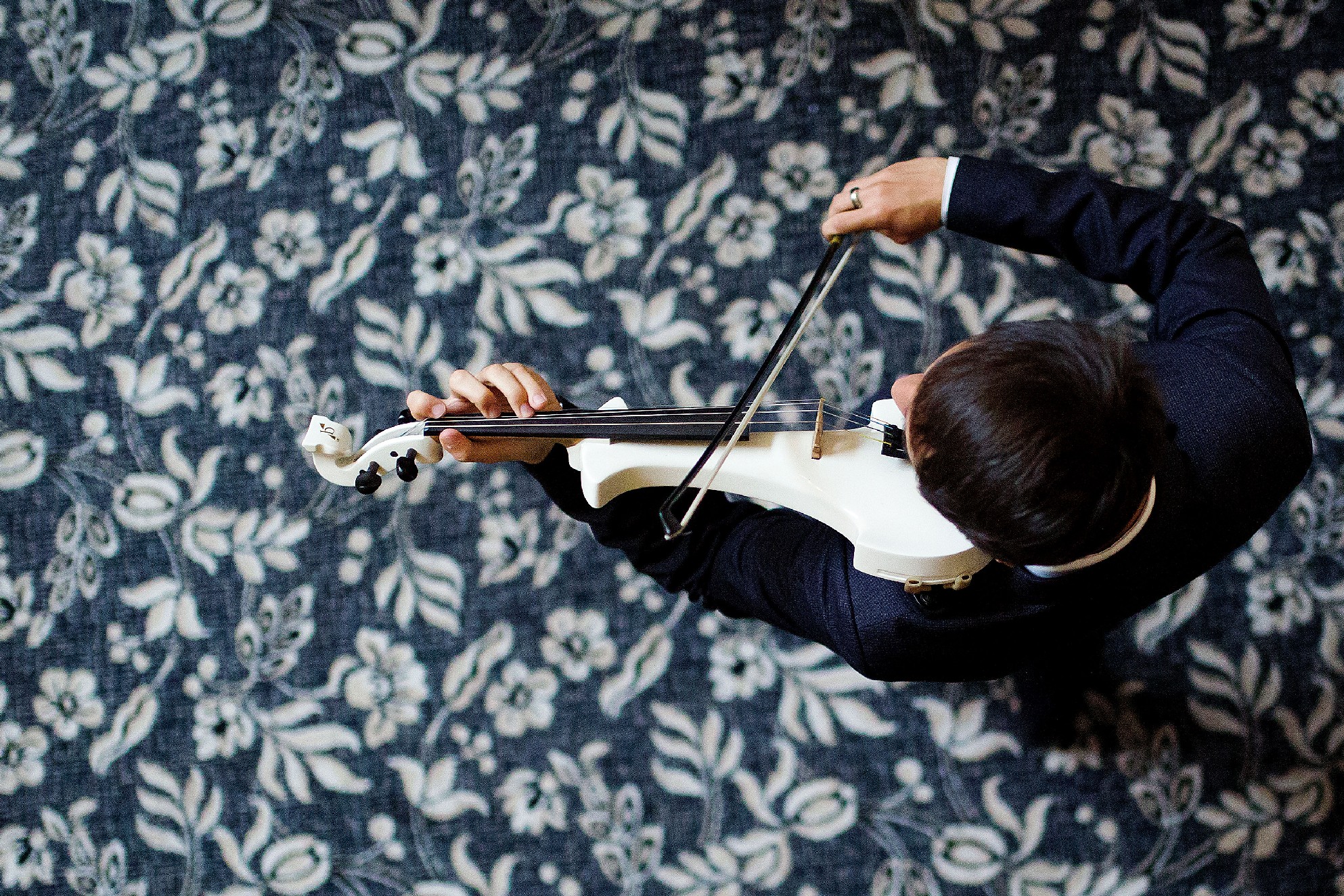 Aerial view of a young male violinist playing on a blue and cream patterned carpet 