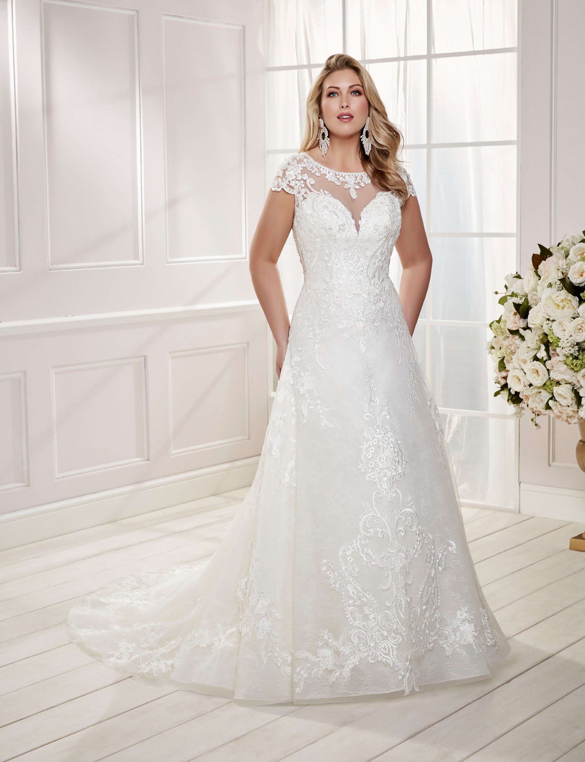 Curvy model in Ronald Joyce plus size wedding dress style 69475, an ivory A-line dress with a sweetheart illusion neckline and beautiful embroidery 