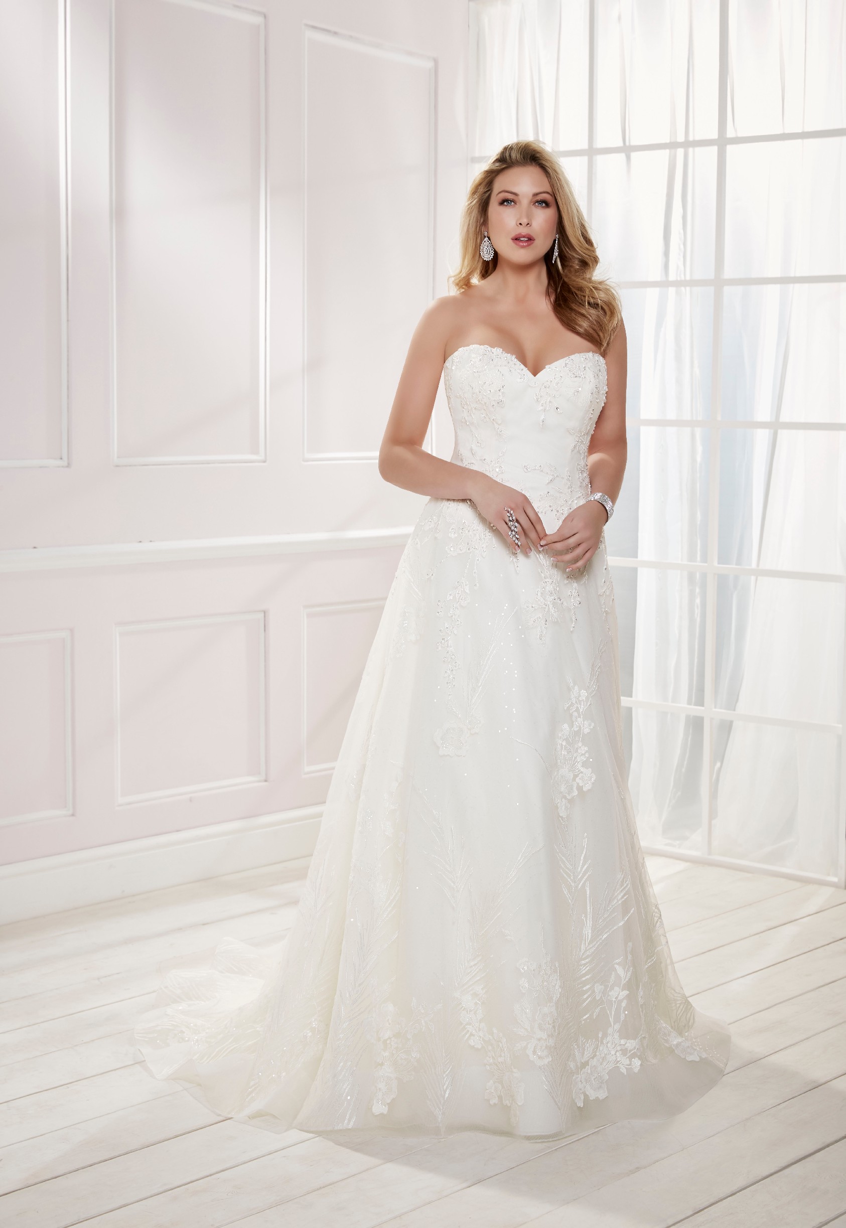 Curvy model in Ronald Joyce plus size wedding dress style 69476, an ivory strapless sweetheart A-line dress with sparkle sequins and lace appliques