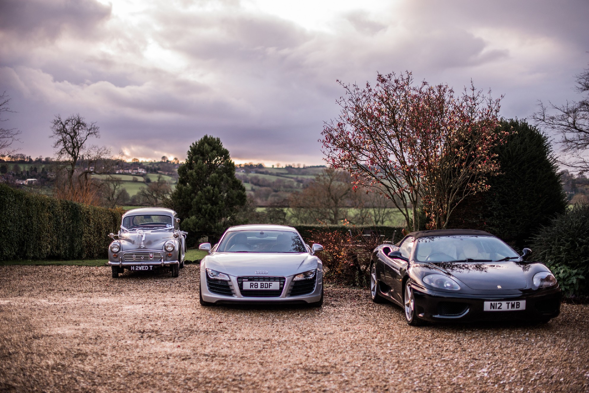 A grey classic wedding car parked next to two expensive sports cars - a grey Audi and a black Porche.jpg