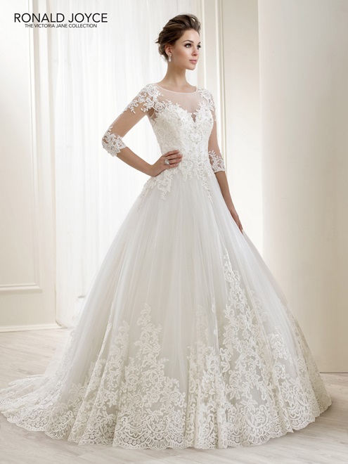 Model wearing Ronald Joyce 18171, a ballgown winter wedding dress with a lace hem, ¾ lace illusion sleeves and sheer illusion sweetheart neckline
